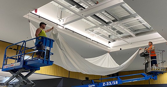 Unfolding the stretch ceiling film and fixing its four corners
